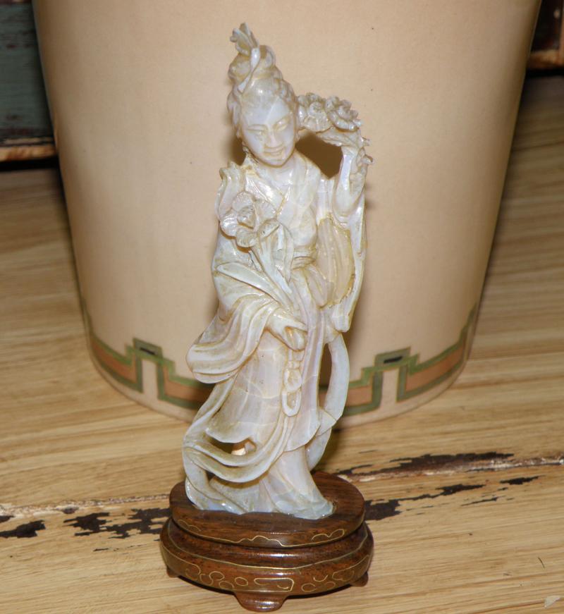 Large Carved Opal Figurine on Stand   in front of vase 